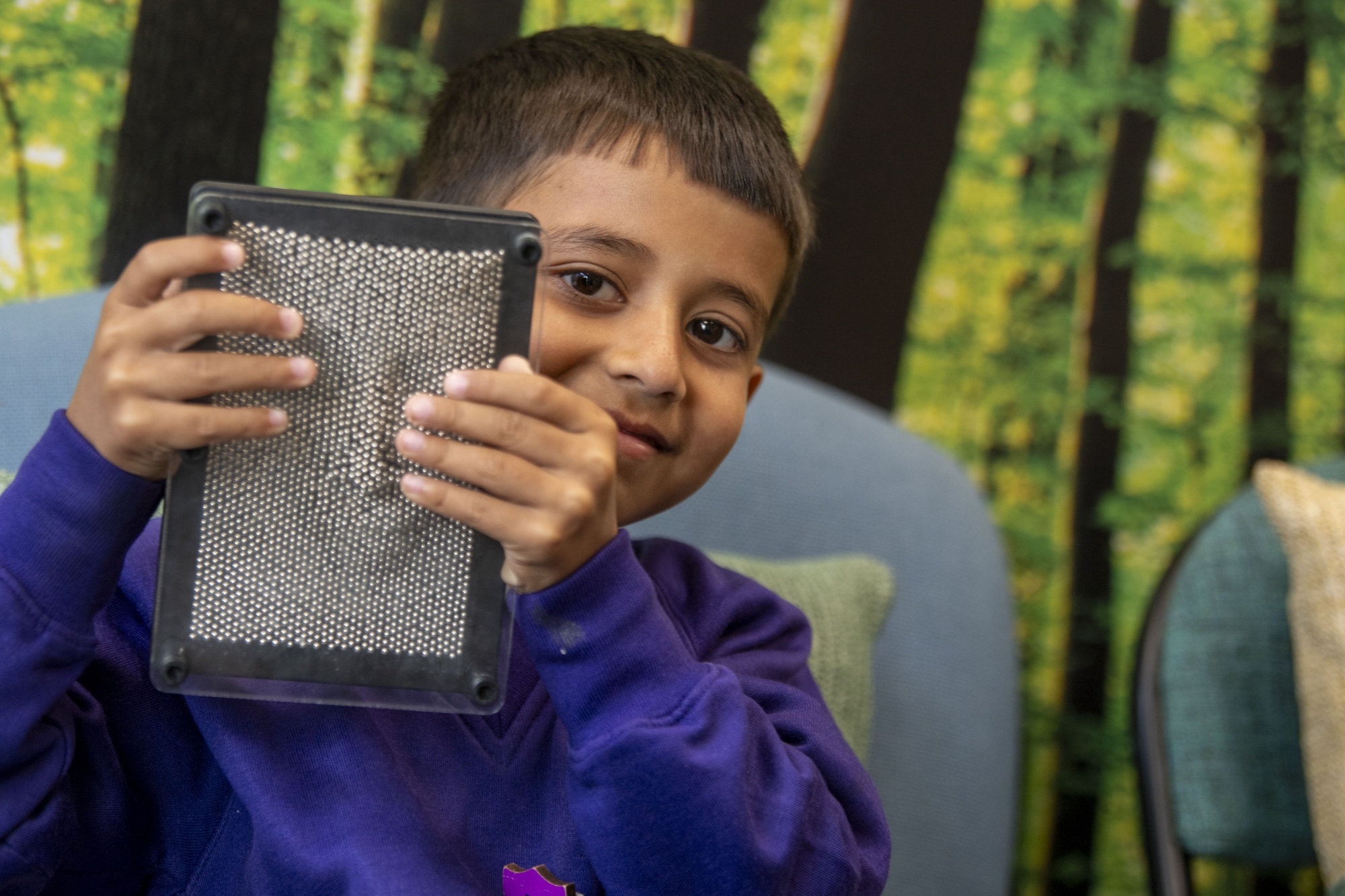 A boy in Castercliff uniform holding up a magnetic toy