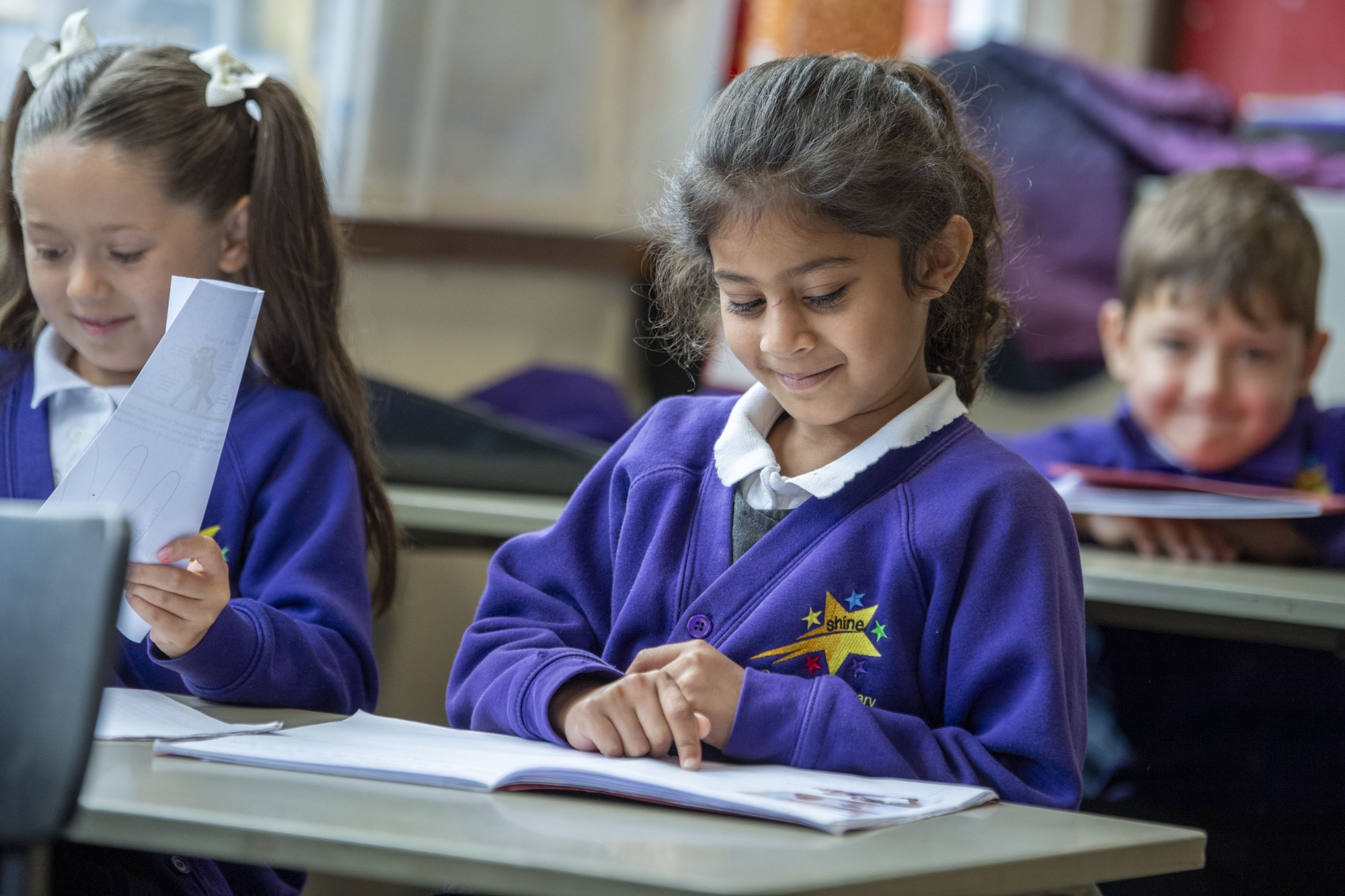 Children in Castercliff uniform looking at their workbooks in a classroom